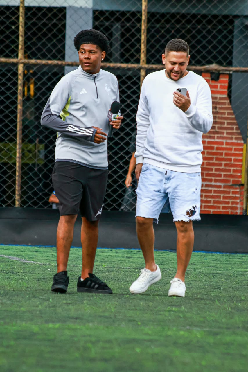 Teodoro conversando com um jogador em um campo de futebol.