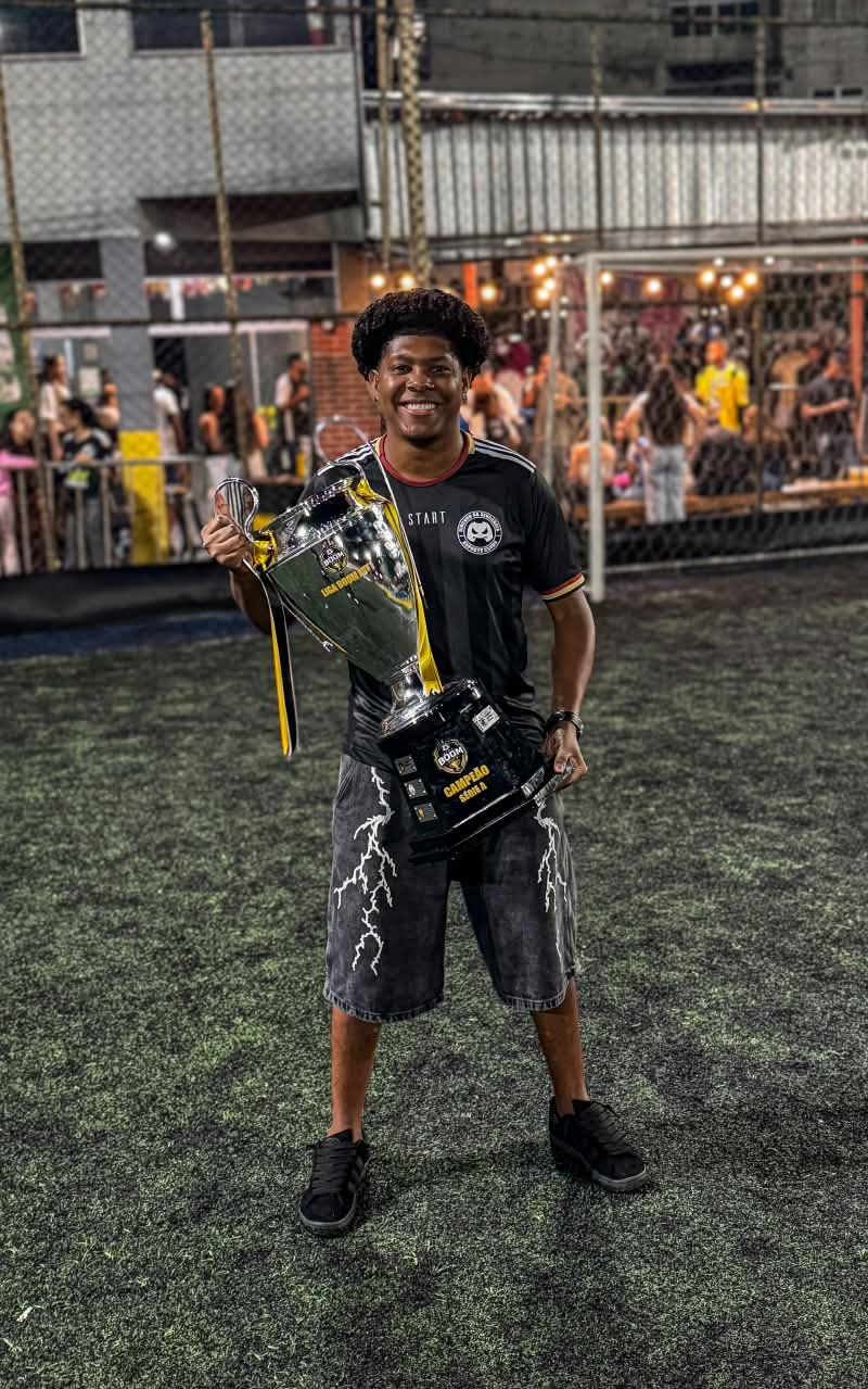 Teodoro com um troféu nas mãos, em um campo à noite.
